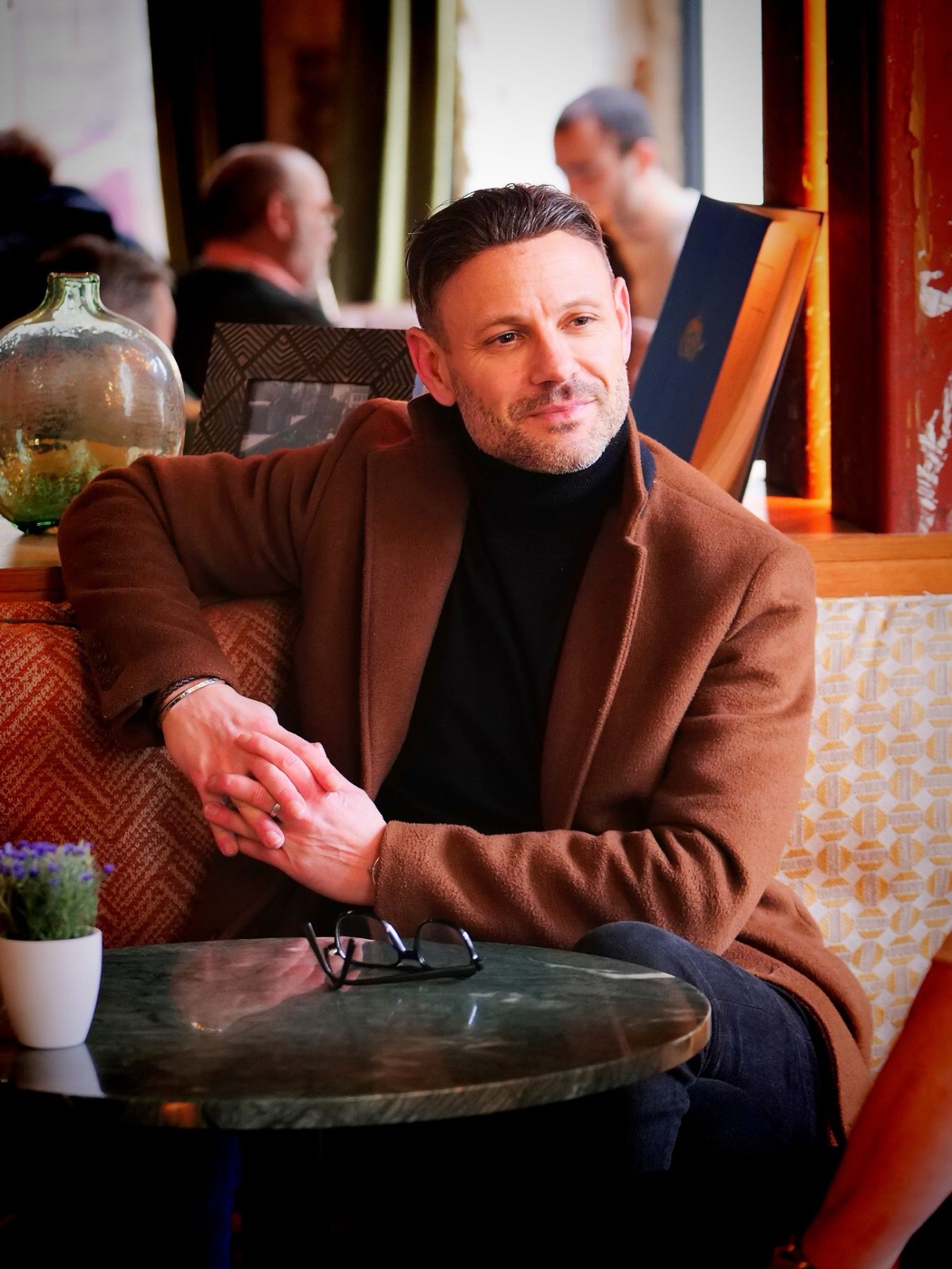 David, coach de L'Homme Nouveau, assis à une table de café